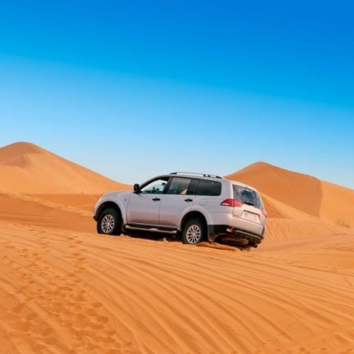 Mitsubishi Pajero driving across the Sahara dunes during off road adventure featured in 15 days desert tour from Casablanca experience.